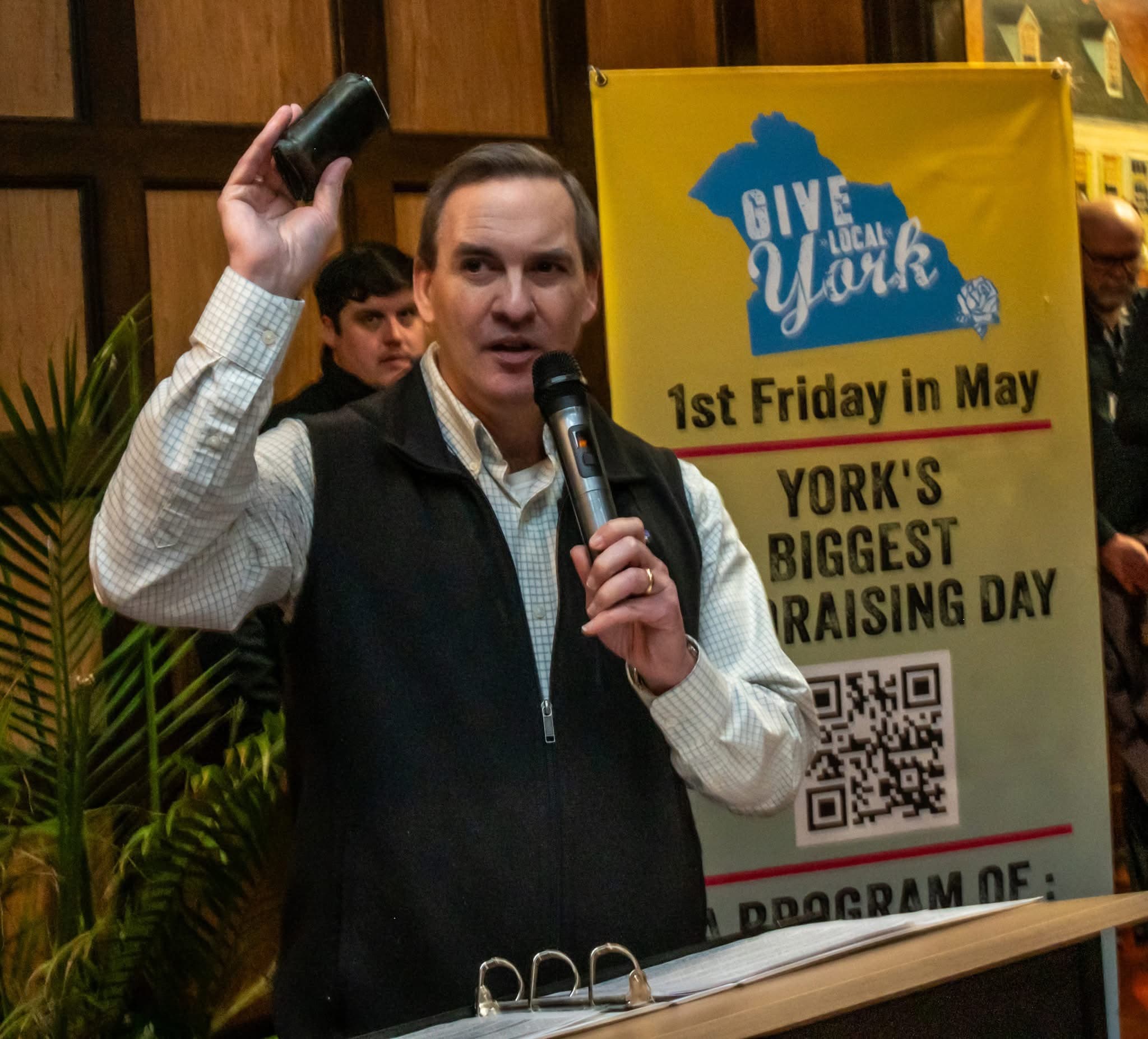 Kevin Smith holding up the returned wallet while telling the story at a Give Local York fundraising event